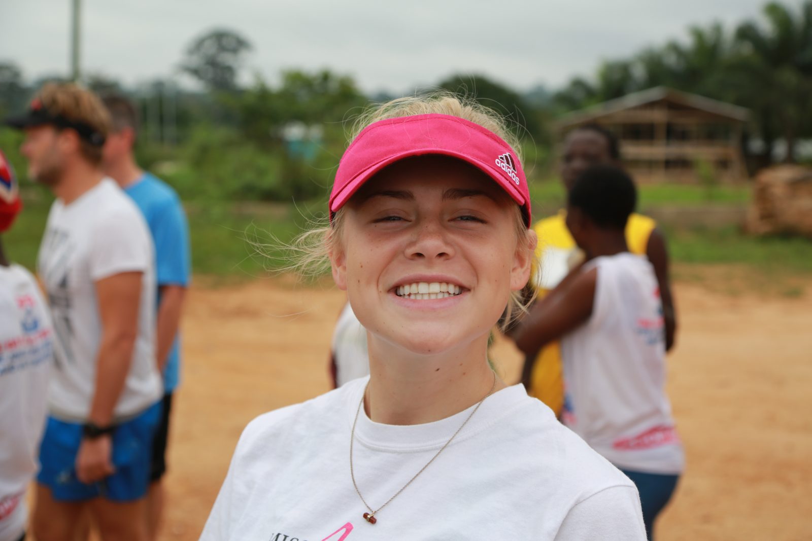 A smiling volunteer in a pink visor at the staging area