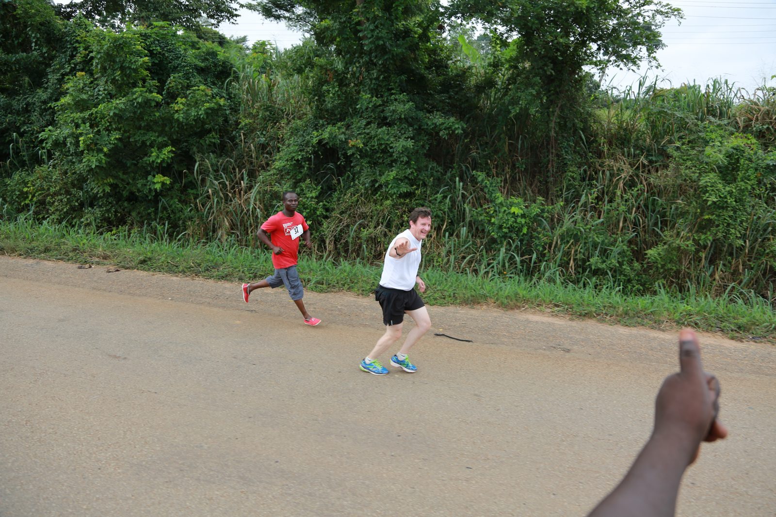 A runner waves to the camera mid-race