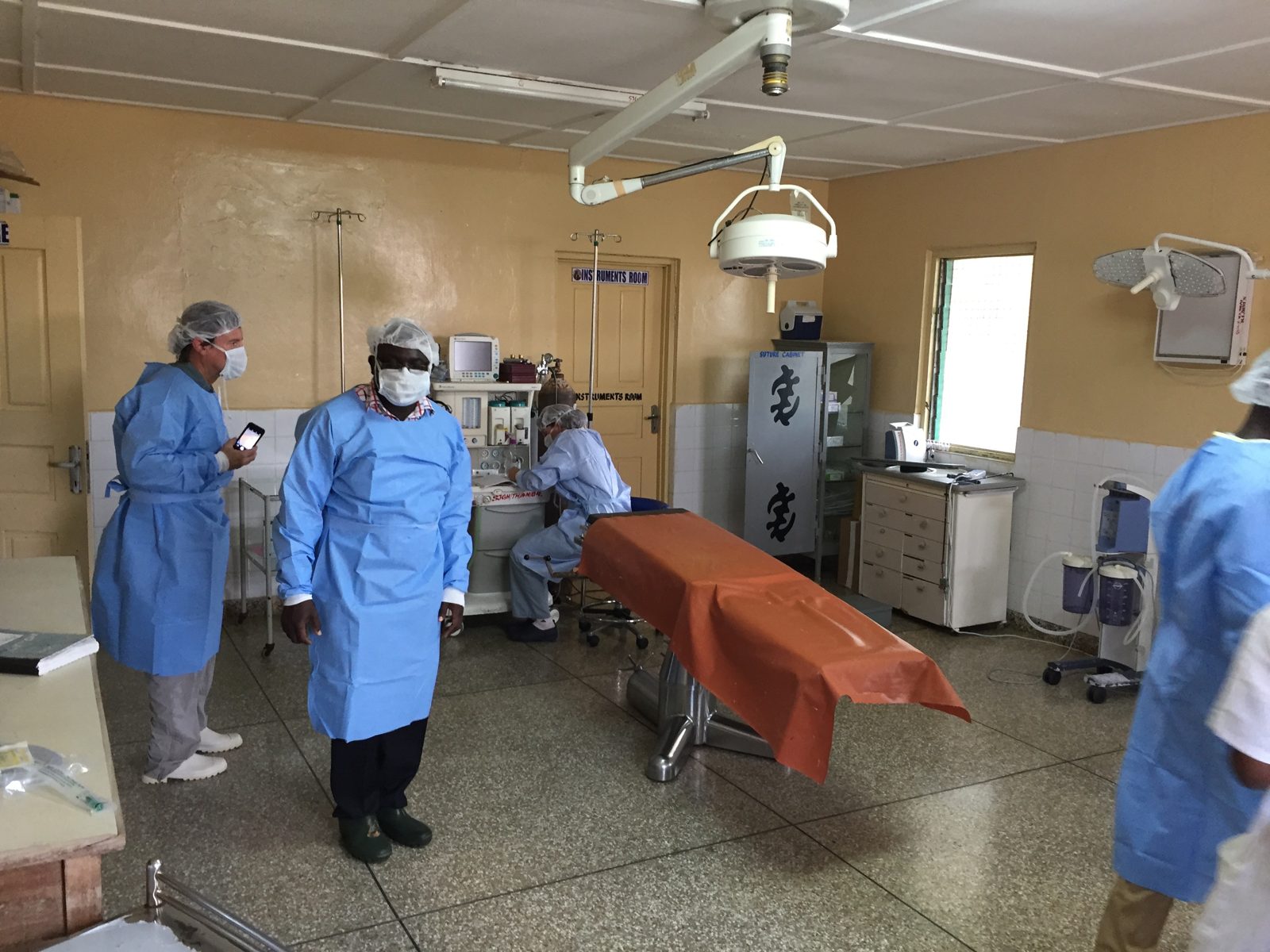 Visiting and local clinicians in blue gowns working a case together