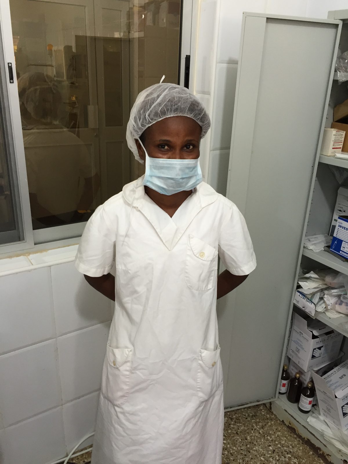 A nurse in whites and surgical cap in the hospital supply room