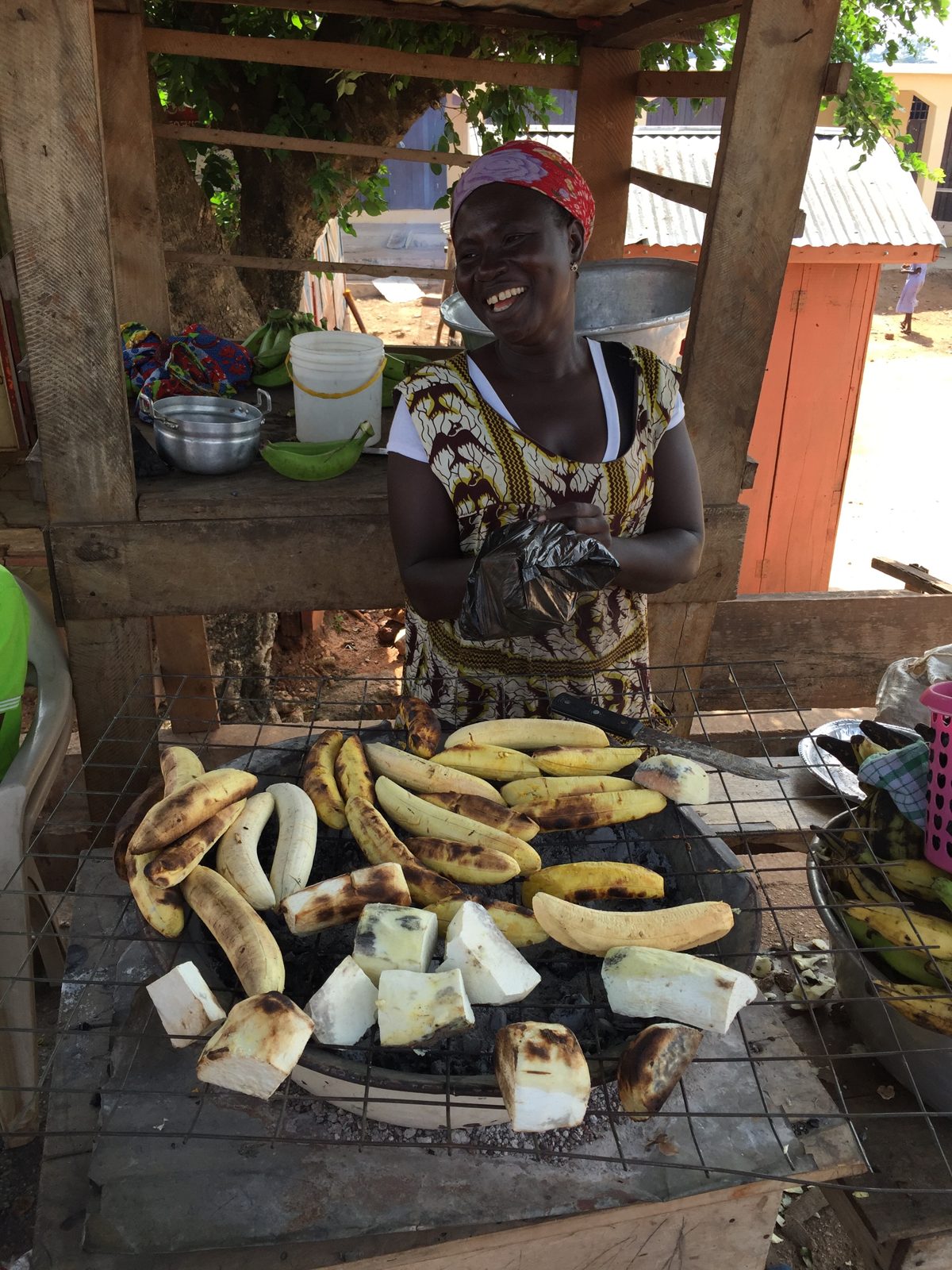 A woman roasting plantain at a roadside stand