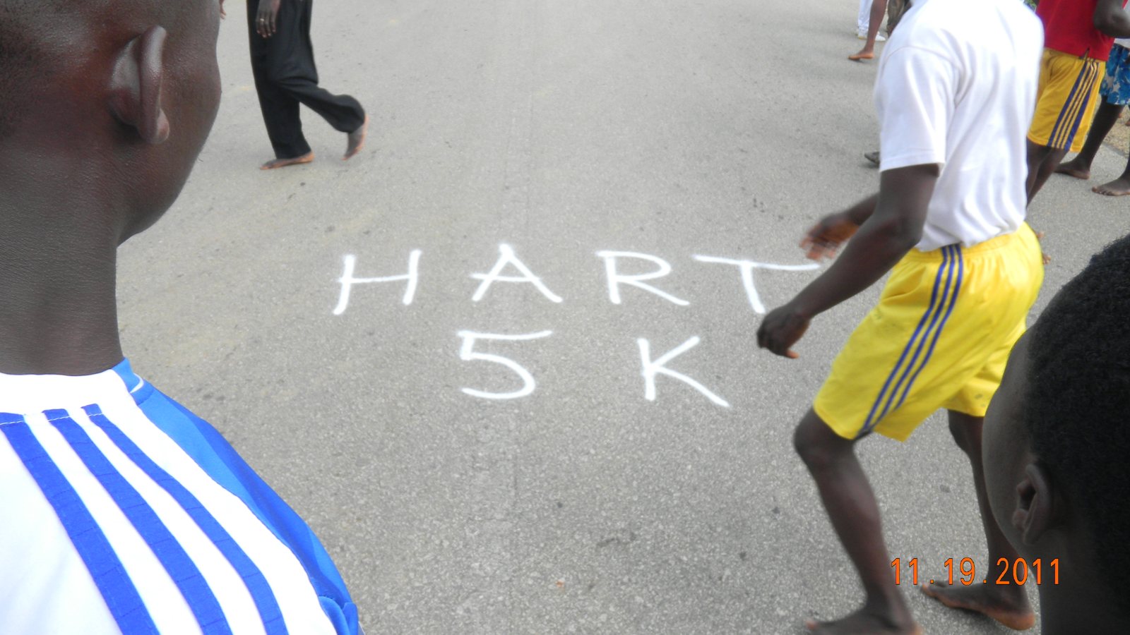HART 5K painted on the road as barefoot runners cross it