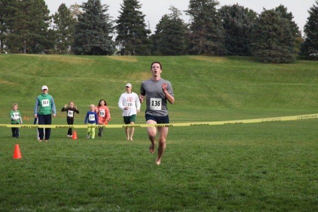 A runner striding to the finish line on the grass